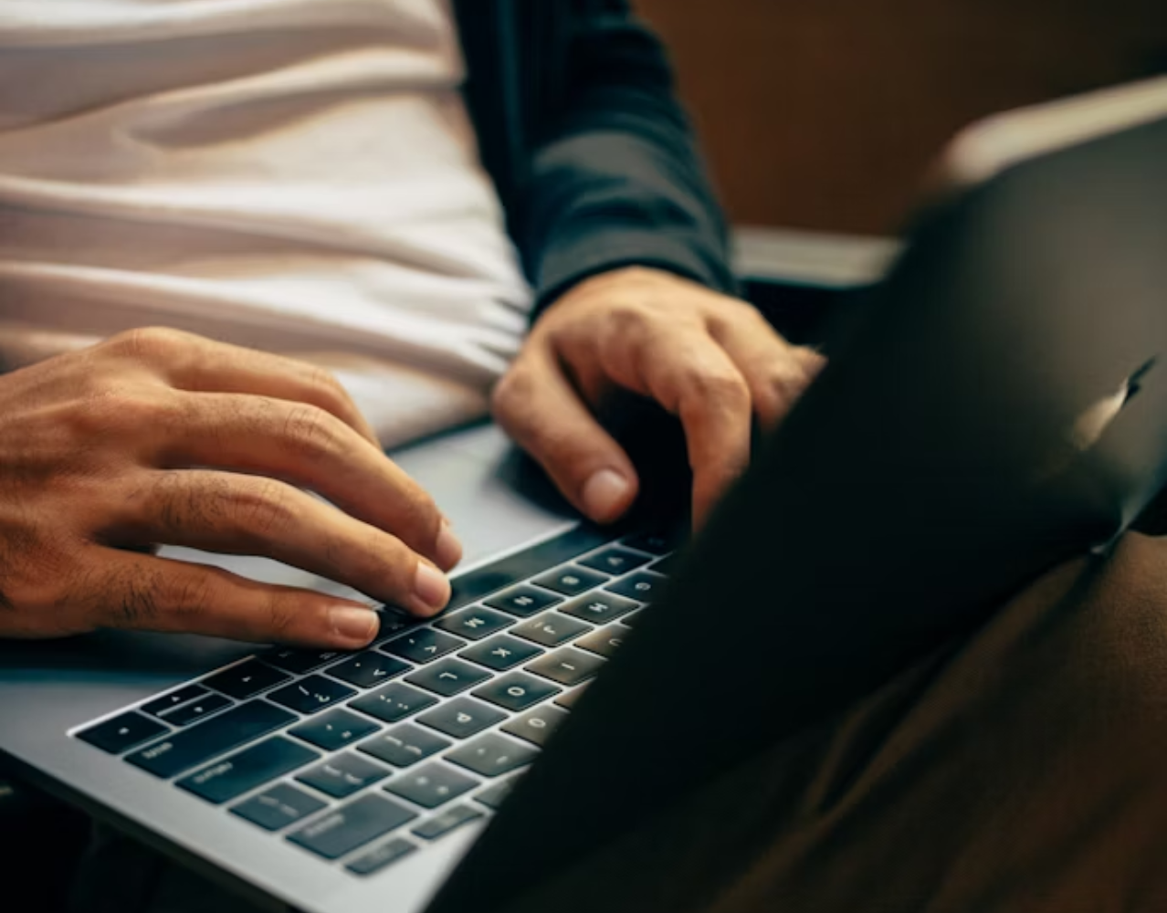 a person is typing on a laptop with the shift key visible